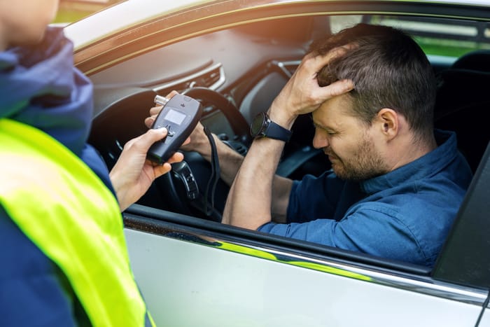 drunk man sitting in the car after police alcohol test with alcometer